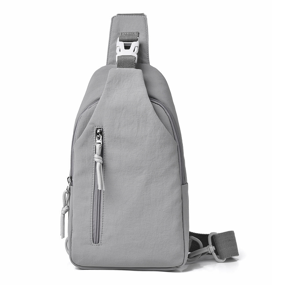 A light gray sling backpack with a single shoulder strap, adjustable buckle, and a vertical zippered pocket on the front, shown against a plain white background.