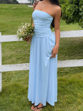 Woman in a light blue strapless dress standing in a grassy area with a white fence.