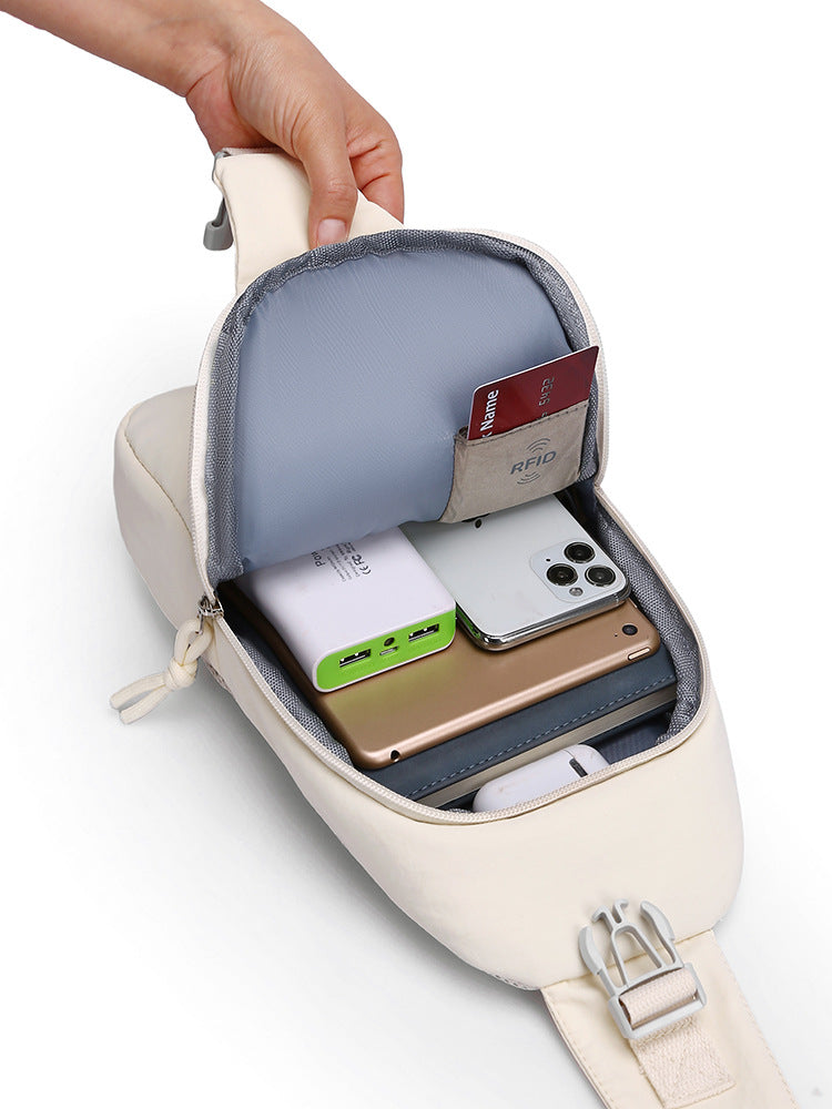 Small beige backpack with compartments containing electronic devices on a white background