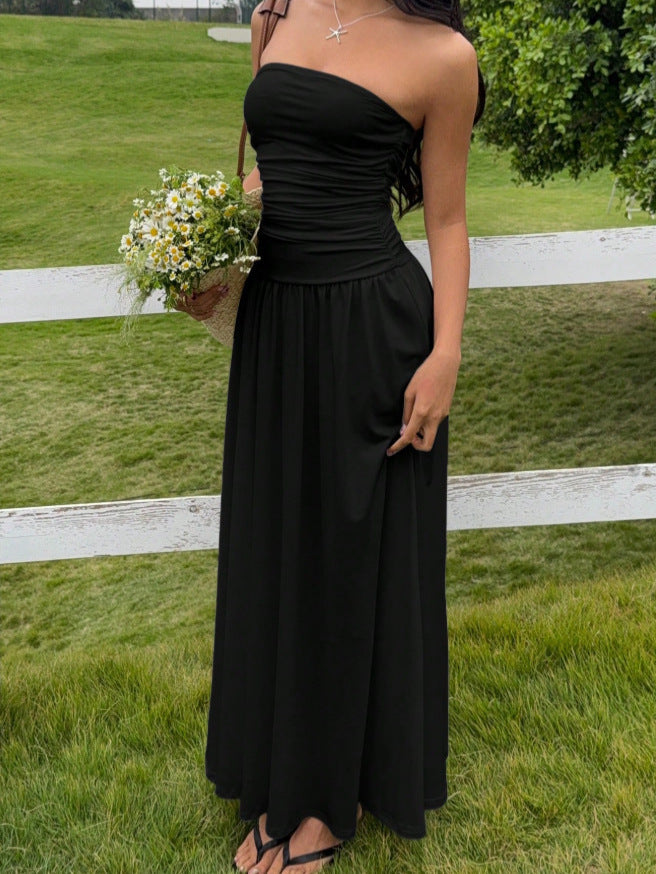 Woman in a black strapless dress holding flowers outdoors.