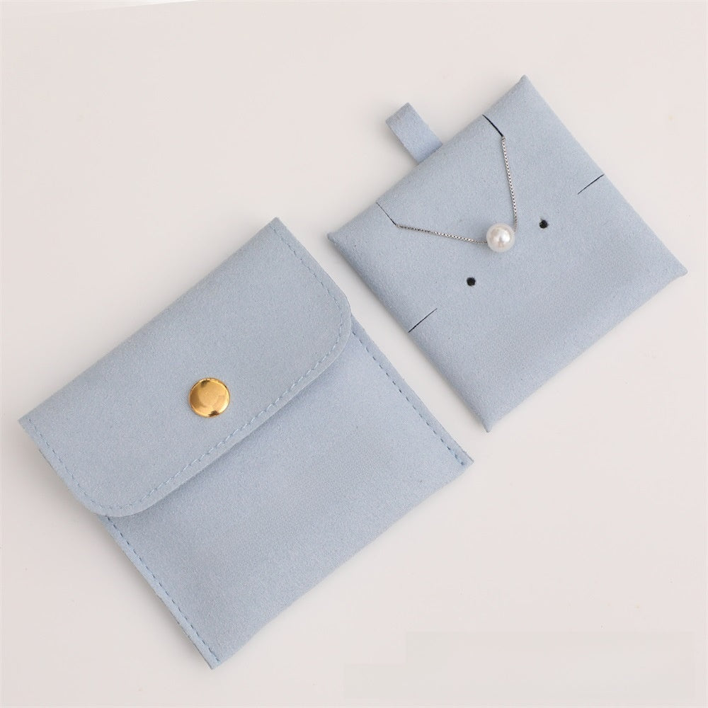 Two light blue jewelry pouches with a necklace and round object on a white background