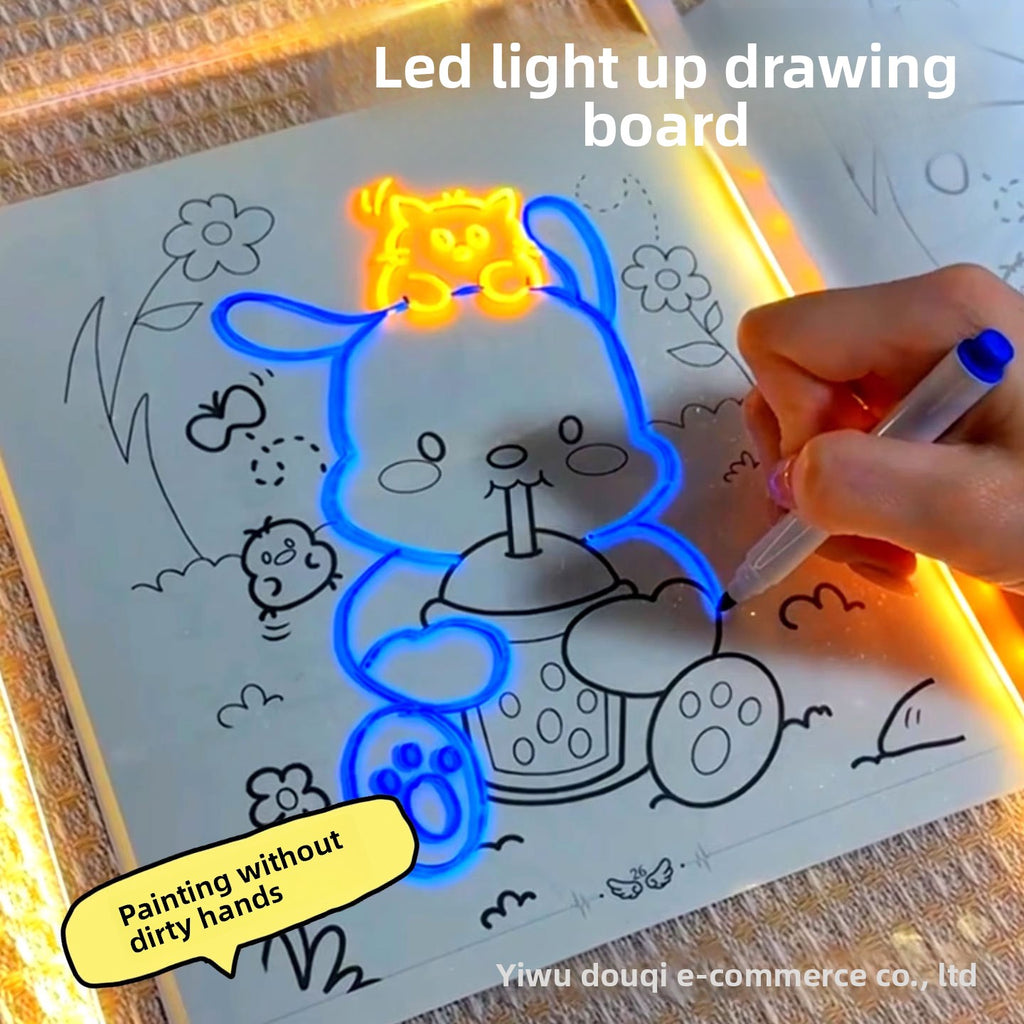 LED light-up drawing board with a hand drawing a blue cat character on a coloring book page.