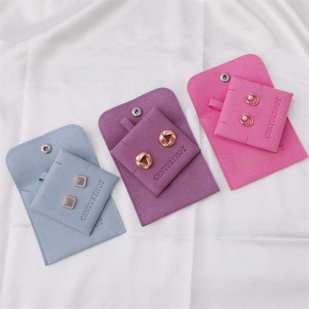 Three jewelry pouches in blue, purple, and pink with earrings on a white background