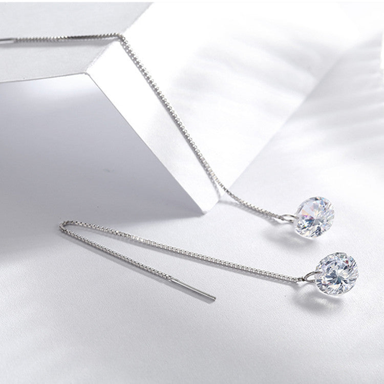 Silver earrings with clear gemstones on a light gray background