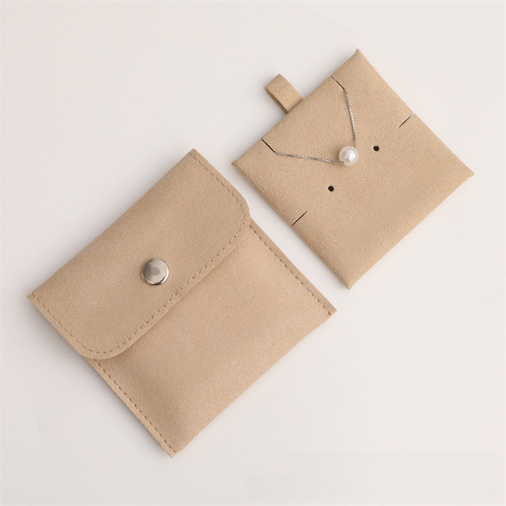 Two beige jewelry pouches with a necklace on a light background