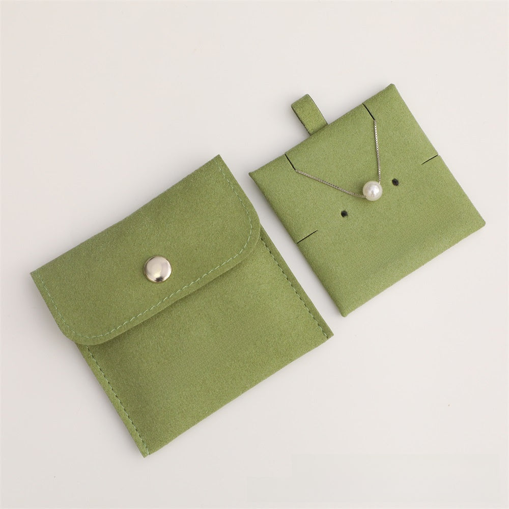 Green jewelry pouch with a necklace on a light gray background