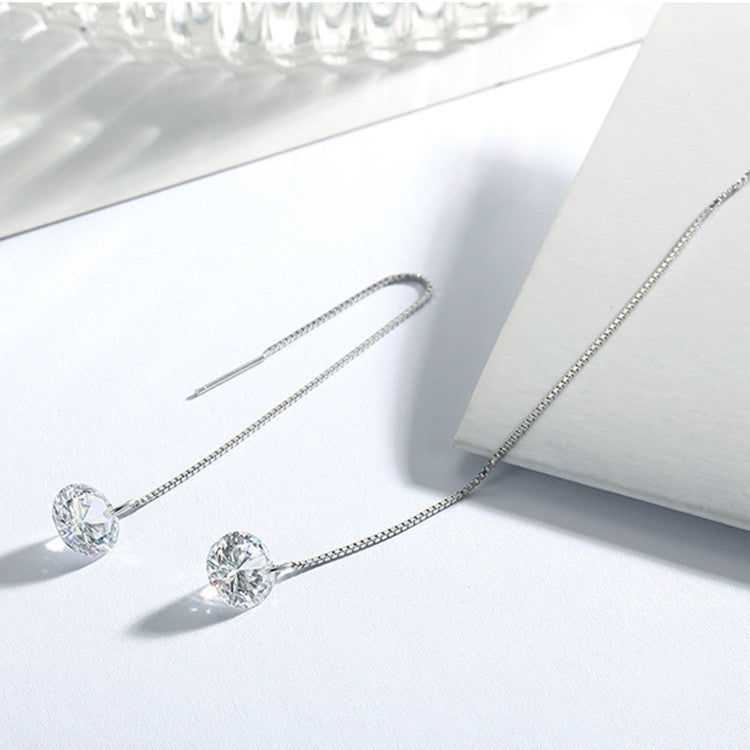 Silver earrings with clear gemstones on a white surface