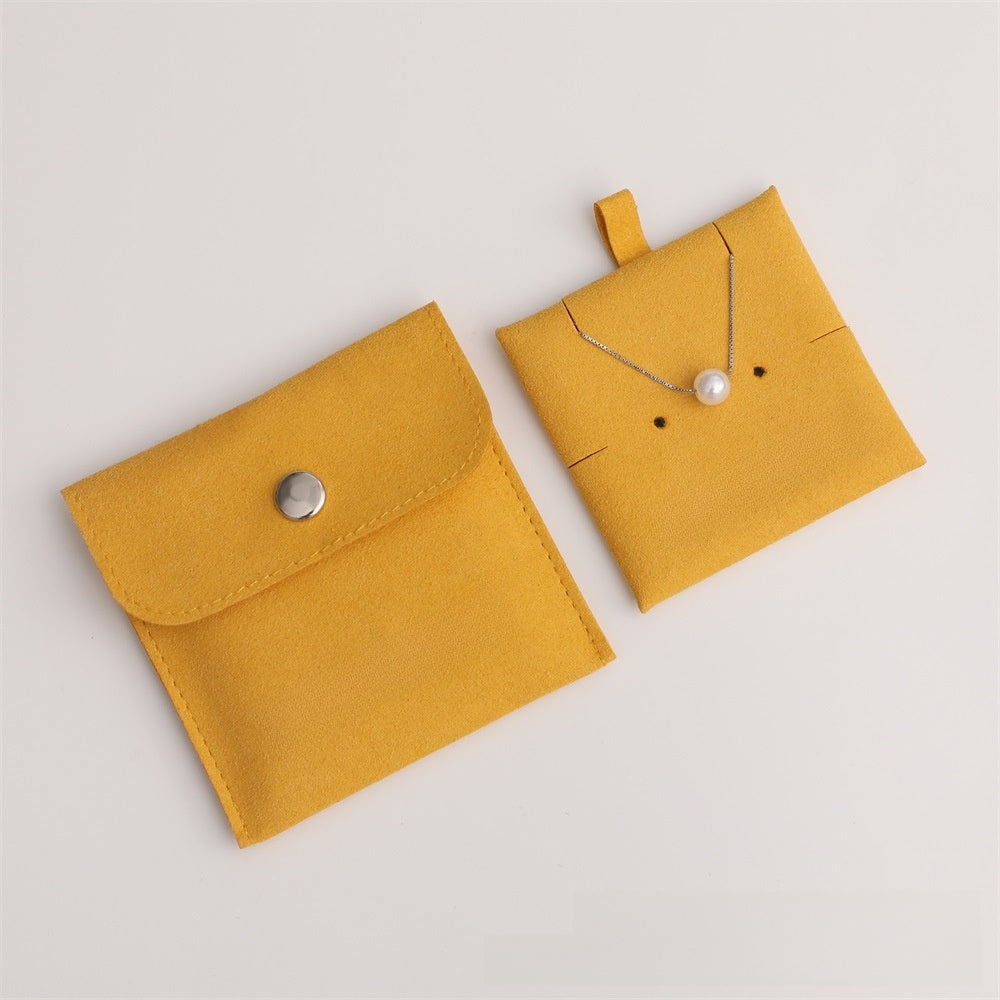 Yellow jewelry pouch with a necklace on a light gray background