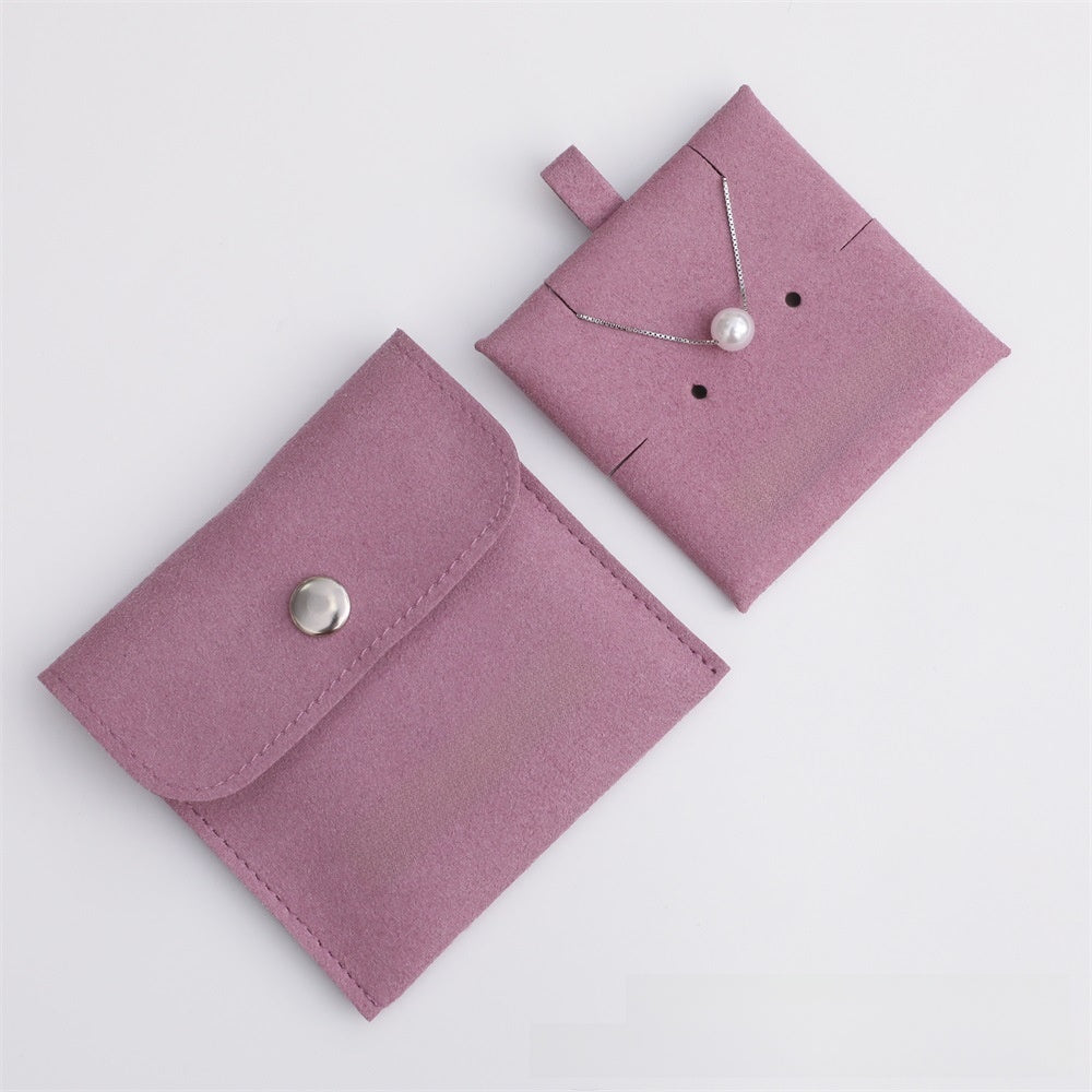 Pink jewelry pouch with a necklace on a light gray background